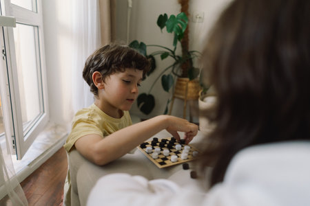 Teenage Girl and Boy Playing Board Game checkers In Living Roomの写真素材