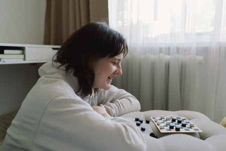 Teenage Girl and Boy Playing Board Game checkers In Living Room