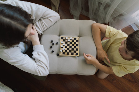 Teenage Girl and Boy Playing Board Game checkers In Living Roomの写真素材