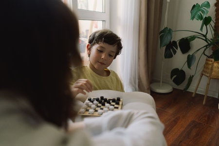 Teenage Girl and Boy Playing Board Game checkers In Living Room