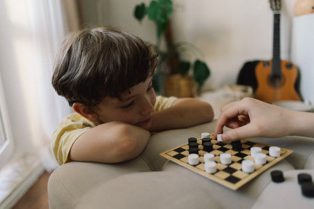 Teenage Girl and Boy Playing Board Game checkers In Living Roomの写真素材