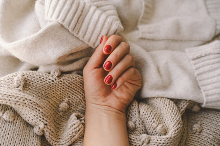 Cozy winter setting with a hand displaying red nail polishの写真素材