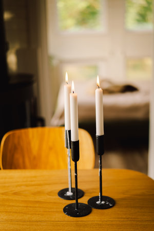 Three lit candles on a wooden table creating a cozy atmosphereの写真素材