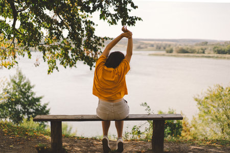 A woman enjoys a peaceful moment by the riversideの写真素材