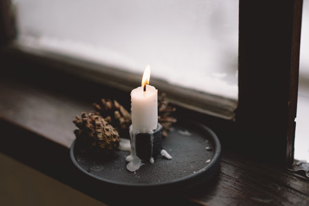 A warm candle flame flickers against a soft backdropの写真素材