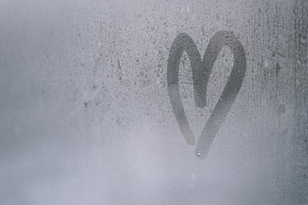 Heart shape drawn on a foggy windowの写真素材