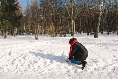 A woman with a red scarf enjoys a snowy winter day in a forest setting beneath a bright blue sky