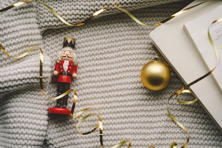 A nutcracker and golden ornament on a cozy knitted blanket during the holiday seasonの写真素材
