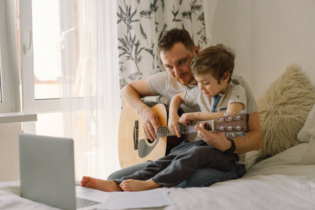 Father and son learn to play the acoustic guitar in an online lesson. Happy Fathers dayの写真素材