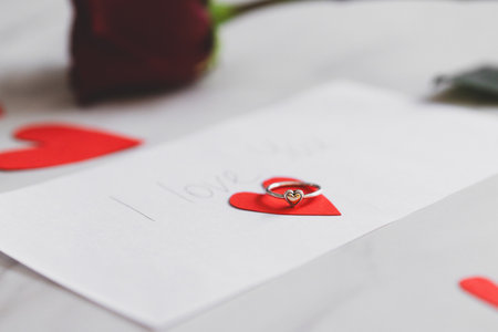 Heartfelt proposal on a handwritten note with a ring on a red paper heartの写真素材