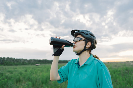 Woman in Helmet Takes a Drink During a Bike Rideの写真素材