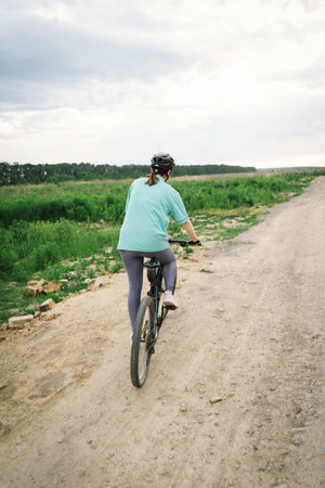 Woman Riding a Mountain Bike on a Dirt Path Near Suburbiaの写真素材