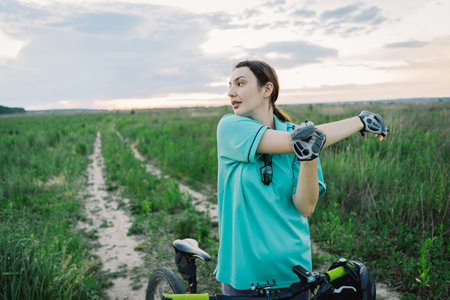 Woman Stretching Before Bike Ride in Green Fieldの写真素材