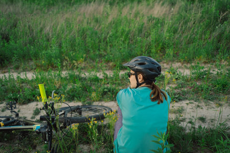 Woman Rests Beside Her Bicycle in a Fieldの写真素材