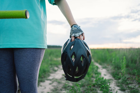Woman Holding Bike Helmet and Glasses on a Dirt Pathの写真素材