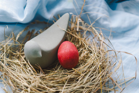 Colorful Easter eggs nestled in a nest surrounded by straw on a light blue background