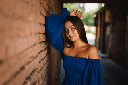 Portrait happy young woman wearing blue dress looking at camera standing. Urban backgroundの写真素材