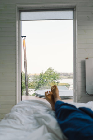 Relaxed feet resting on a clean, white bedspread in a calm bedroom environmentの写真素材