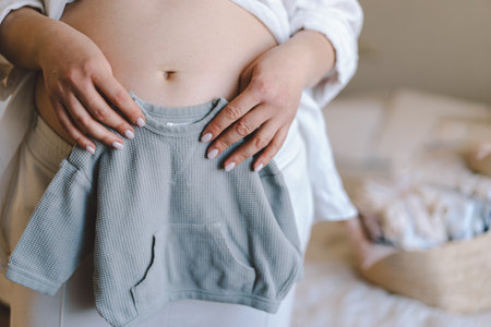 Expecting mother holds baby sweater near her bellyの写真素材