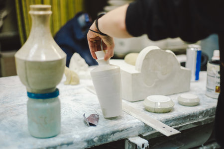 A skilled artisan carefully applies glaze to a ceramic vaseの写真素材