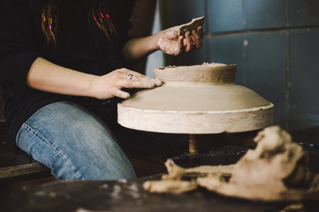 Hands skillfully shape a clay pot in a pottery studio