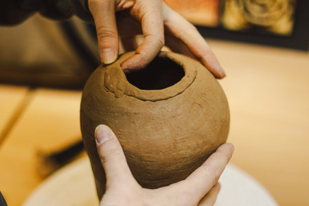 Hands skillfully shape a clay pot in a pottery studioの写真素材