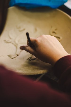 Crafting intricate designs on pottery in an art studio during a creative workshop sessionの写真素材