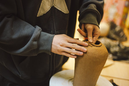 Hands skillfully shape a clay pot in a pottery studio