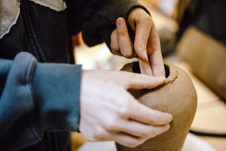 Hands skillfully shape a clay pot in a pottery studio