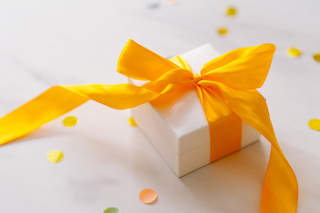 Gift box with long yellow ribbon and tulipsの写真素材