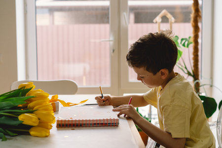 A boy diligently creating a heartfelt Mothers Day cardの写真素材