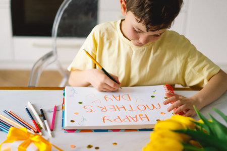 A boy diligently creating a heartfelt Mothers Day cardの写真素材
