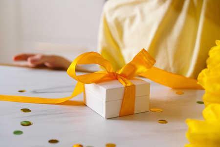 A boy carefully tying a bow on a Mothers Day gift