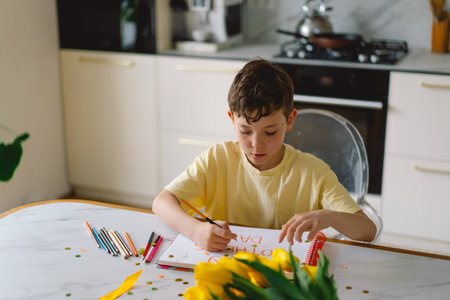 A boy diligently creating a heartfelt Mothers Day cardの写真素材