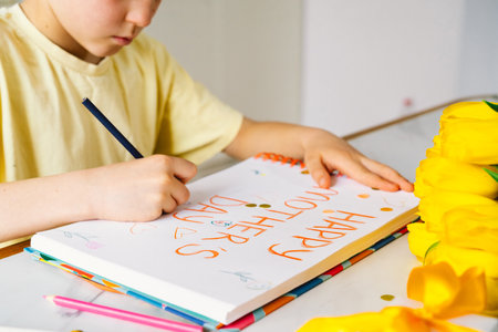 A boy diligently creating a heartfelt Mothers Day cardの写真素材