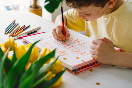A boy diligently creating a heartfelt Mothers Day cardの写真素材
