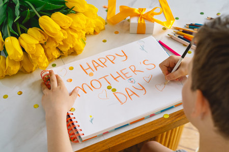 A boy diligently creating a heartfelt Mothers Day cardの写真素材