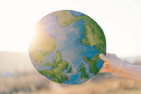 Woman holding planet in hands against green spring background. Earth day