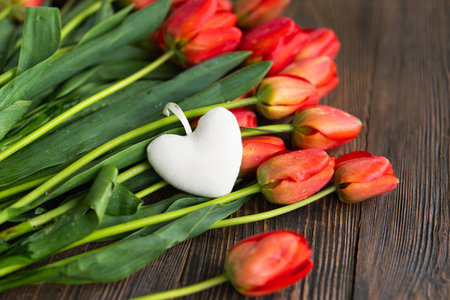 Fresh orange tulips with a white heart on a wood background.の写真素材
