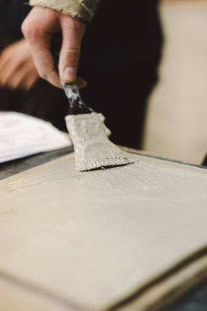 A girl with a brush in her hands works with clayの写真素材