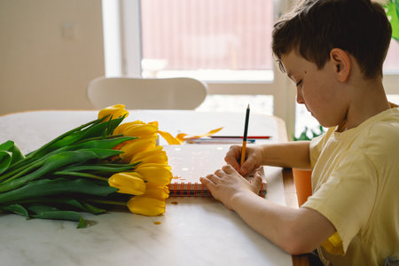 A boy diligently creating a heartfelt Mothers Day cardの写真素材