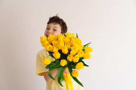 Child joyfully holding a bouquet of vibrant yellow tulipsの写真素材