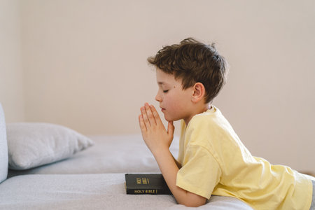 A boy with folded hands in front of him, he prays in his room.の写真素材