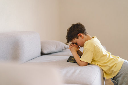 A boy with folded hands in front of him, he prays in his room.の写真素材