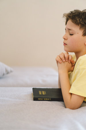A boy with folded hands in front of him, he prays in his room.の写真素材