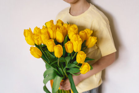 Child joyfully holding a bouquet of vibrant yellow tulipsの写真素材