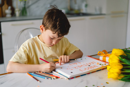 A boy diligently creating a heartfelt Mothers Day cardの写真素材