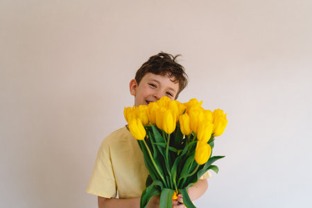 Child joyfully holding a bouquet of vibrant yellow tulipsの写真素材