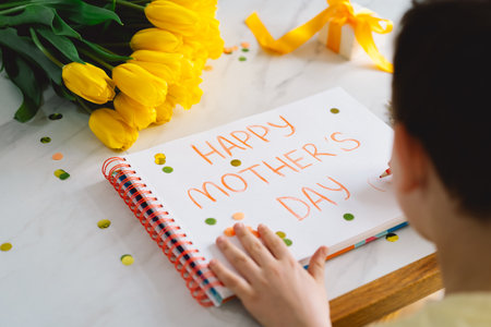 A boy diligently creating a heartfelt Mothers Day cardの写真素材