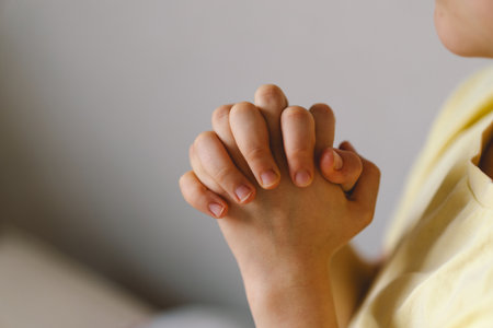 A boy with folded hands in front of him, he prays in his room.の写真素材